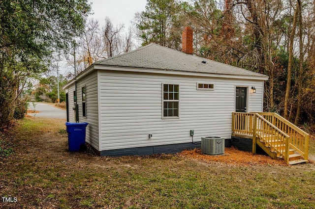 rear view of house featuring central air condition unit and a lawn