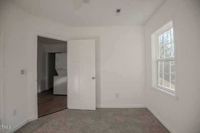 empty room with carpet and stacked washer and clothes dryer