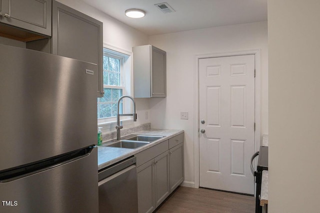 kitchen featuring gray cabinets, sink, light wood-type flooring, and stainless steel appliances