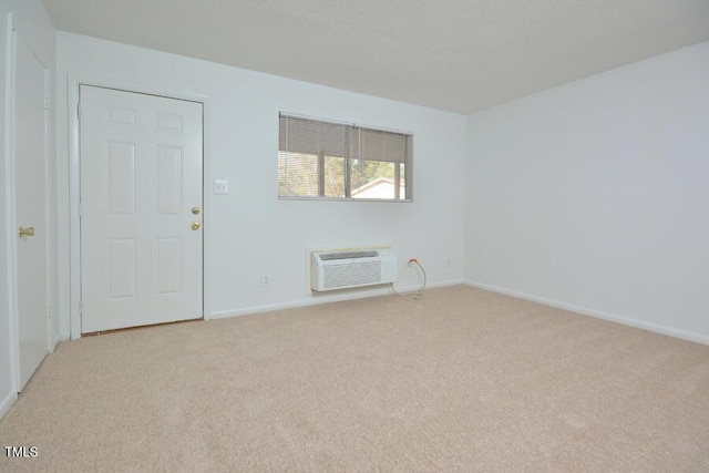 empty room featuring light carpet and a wall mounted air conditioner