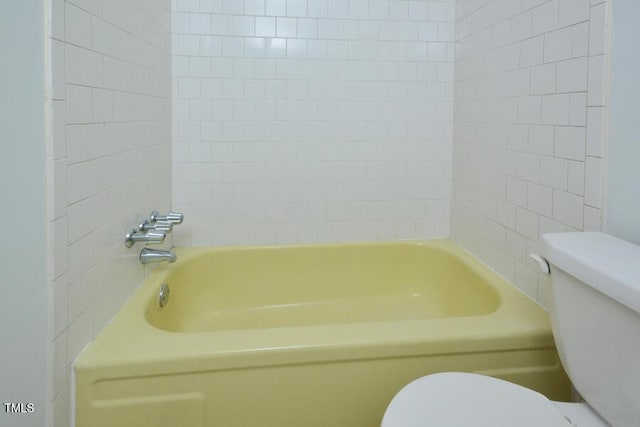 bathroom featuring toilet and tiled shower / bath