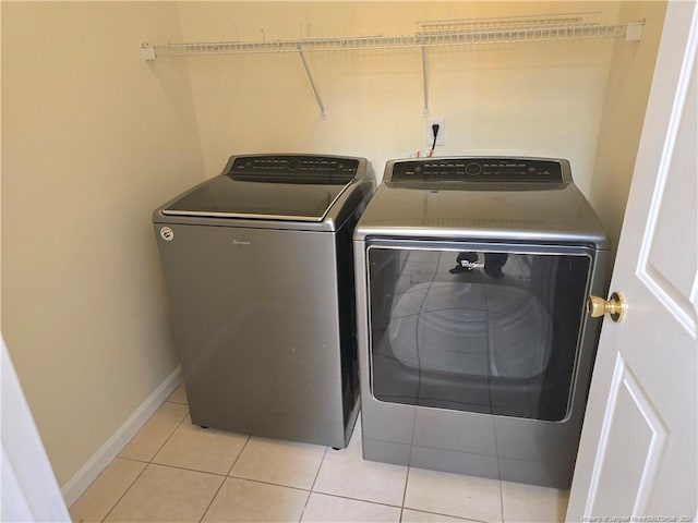 laundry area with washing machine and clothes dryer and light tile patterned floors