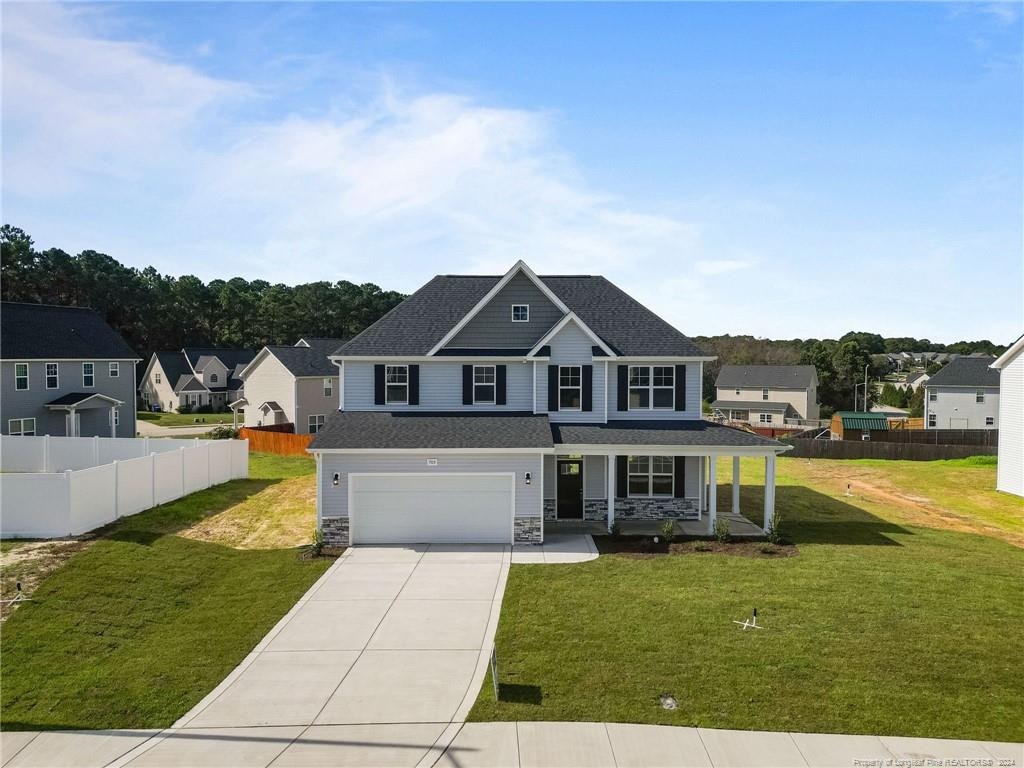 view of front of house featuring a front lawn, covered porch, and a garage