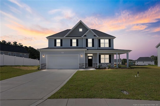 view of front of home with a lawn, covered porch, and a garage