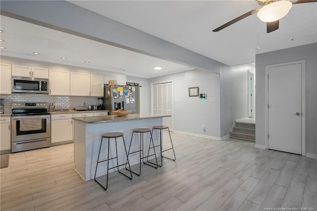 kitchen featuring white cabinetry, a kitchen island, light wood-type flooring, and appliances with stainless steel finishes