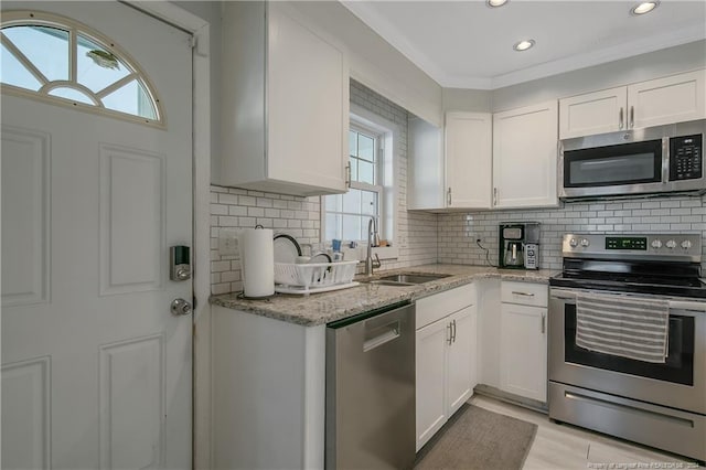 kitchen featuring backsplash, white cabinets, sink, appliances with stainless steel finishes, and light stone counters