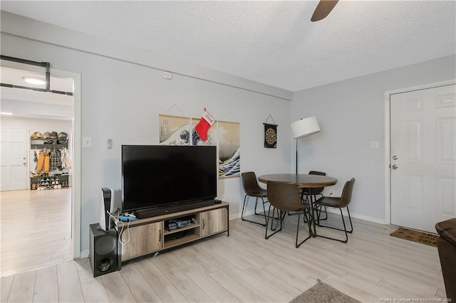 living room featuring a textured ceiling, light hardwood / wood-style flooring, and ceiling fan