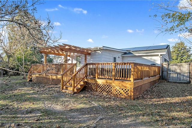 rear view of property featuring solar panels, a deck, and a pergola