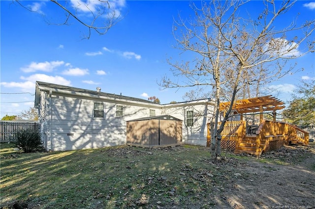 back of property featuring a lawn, a wooden deck, a pergola, and a shed