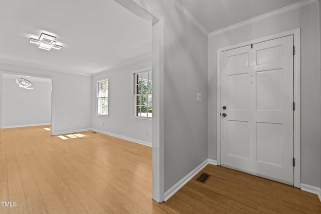 foyer with ornamental molding, light wood finished floors, visible vents, and baseboards