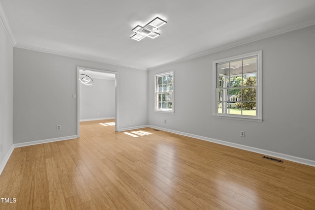 unfurnished room with light wood-type flooring, baseboards, visible vents, and crown molding