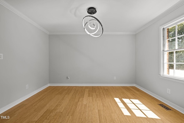 empty room featuring ornamental molding, a wealth of natural light, baseboards, and light wood finished floors