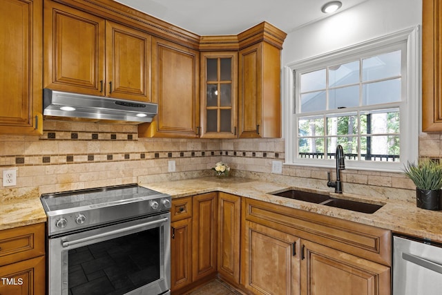 kitchen with stainless steel appliances, brown cabinets, a sink, and under cabinet range hood