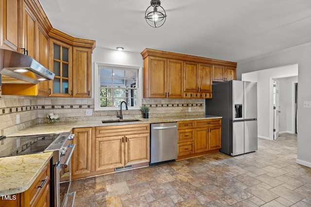 kitchen featuring under cabinet range hood, a sink, appliances with stainless steel finishes, tasteful backsplash, and brown cabinetry