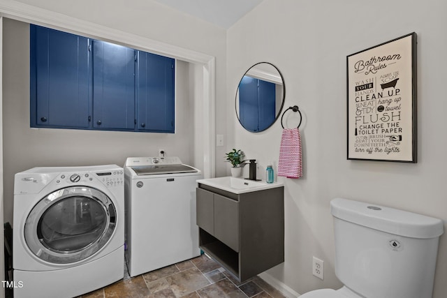 laundry room featuring a sink, laundry area, stone finish floor, and washing machine and dryer