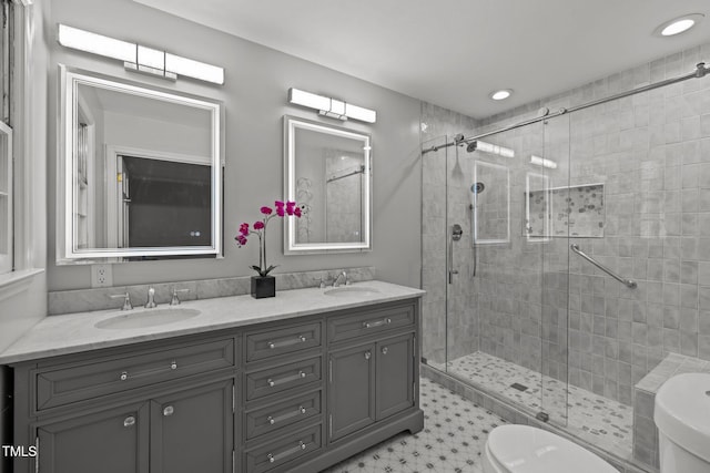 bathroom featuring double vanity, a sink, toilet, and a shower stall