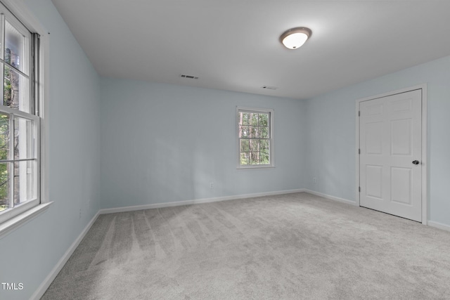 empty room with carpet flooring, visible vents, and baseboards