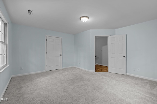 carpeted spare room featuring baseboards and visible vents