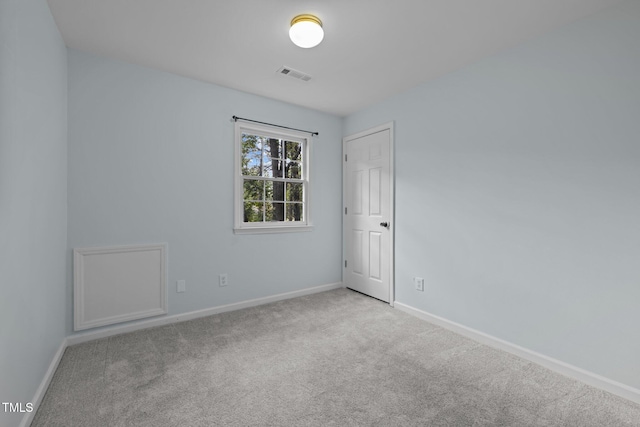 empty room with carpet floors, visible vents, and baseboards