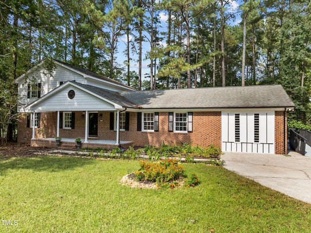 view of front of property featuring a porch, brick siding, driveway, and a front lawn