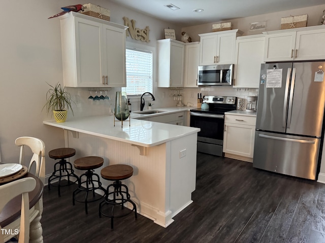 kitchen featuring kitchen peninsula, sink, white cabinets, and stainless steel appliances