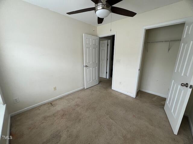 unfurnished bedroom featuring a closet, light colored carpet, and ceiling fan