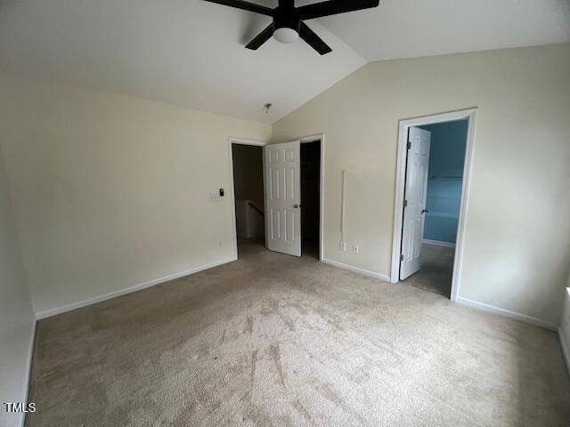 unfurnished bedroom featuring vaulted ceiling, ceiling fan, a spacious closet, light colored carpet, and a closet