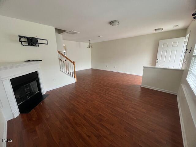 unfurnished living room featuring a chandelier and dark hardwood / wood-style floors