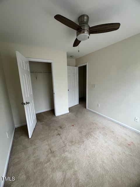 unfurnished bedroom with ceiling fan, light carpet, and a closet