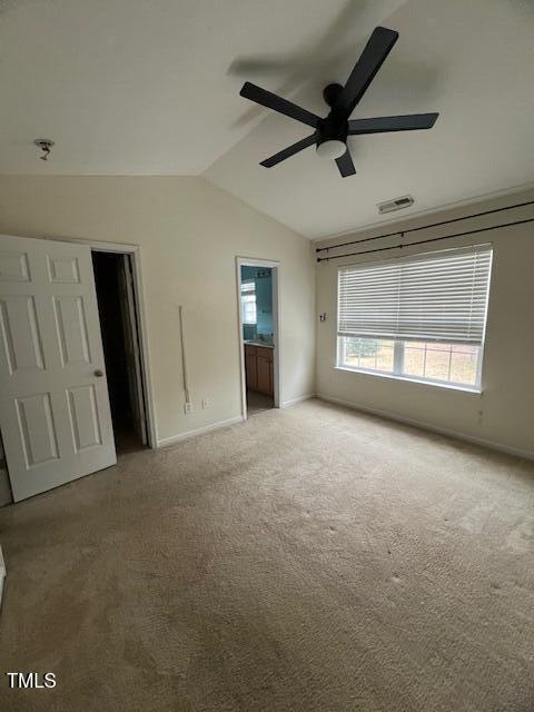 unfurnished bedroom featuring connected bathroom, ceiling fan, carpet floors, vaulted ceiling, and a walk in closet