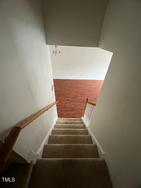 stairway featuring a notable chandelier and wood-type flooring