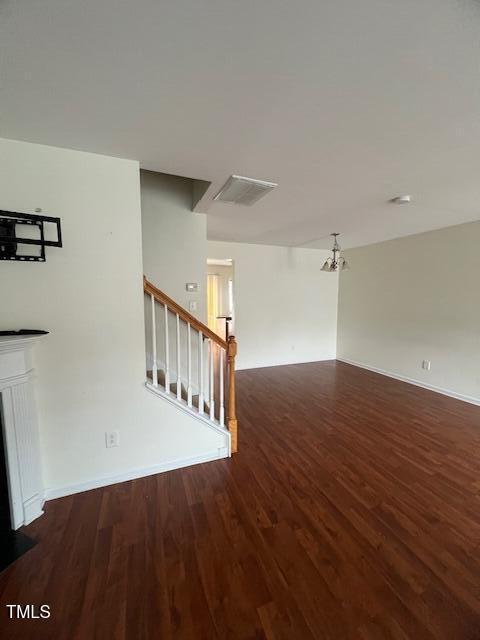 unfurnished living room with dark hardwood / wood-style flooring and an inviting chandelier