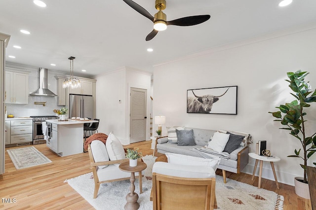 living room with light hardwood / wood-style flooring, ceiling fan with notable chandelier, and ornamental molding