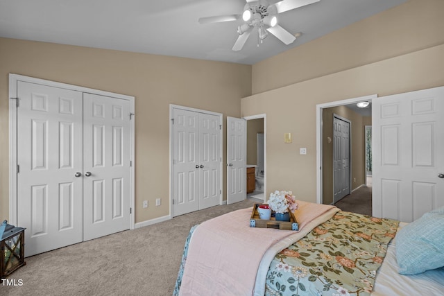 bedroom featuring ceiling fan, vaulted ceiling, carpet floors, and multiple closets