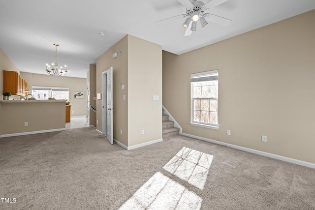 spare room featuring light colored carpet and ceiling fan with notable chandelier