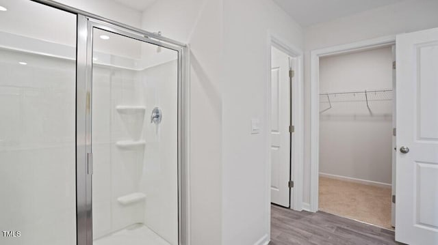 bathroom with a shower with door and wood-type flooring