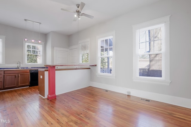 kitchen with a breakfast bar, decorative light fixtures, dishwasher, wood-type flooring, and kitchen peninsula