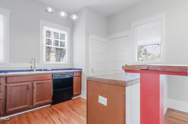 kitchen featuring decorative light fixtures, dishwasher, sink, and light wood-type flooring