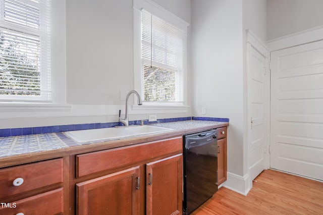 kitchen with sink, light hardwood / wood-style floors, and black dishwasher