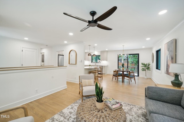 living room with ceiling fan, crown molding, and light hardwood / wood-style floors