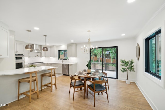 dining space featuring crown molding, a healthy amount of sunlight, an inviting chandelier, and light hardwood / wood-style floors