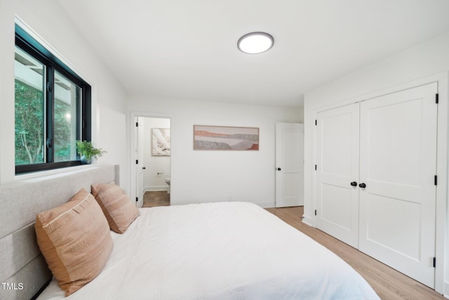 bedroom featuring a closet, ensuite bathroom, and light hardwood / wood-style floors