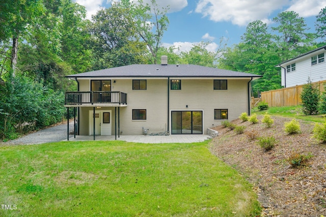 back of house featuring a lawn, a deck, and a patio