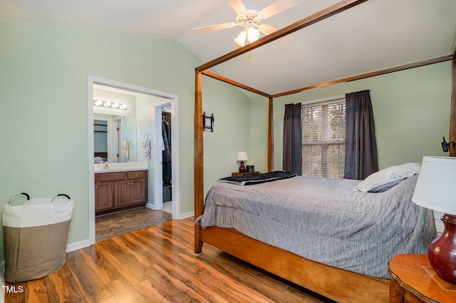 bedroom featuring connected bathroom, sink, vaulted ceiling, ceiling fan, and light hardwood / wood-style flooring