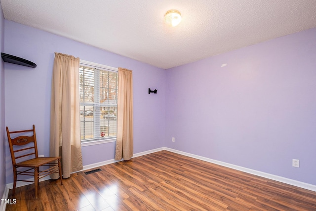 unfurnished room with dark hardwood / wood-style flooring and a textured ceiling