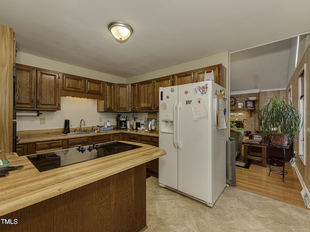 kitchen with sink, white fridge with ice dispenser, black electric cooktop, butcher block countertops, and light hardwood / wood-style floors