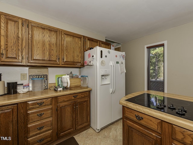 kitchen featuring black electric cooktop and white refrigerator with ice dispenser