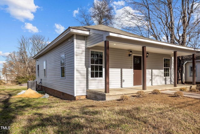 view of front of home with covered porch, cooling unit, and a front yard