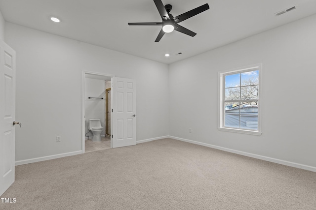 unfurnished bedroom with light carpet, connected bathroom, a spacious closet, and ceiling fan