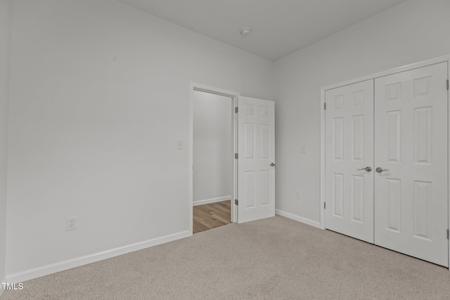 unfurnished bedroom featuring light colored carpet and a closet